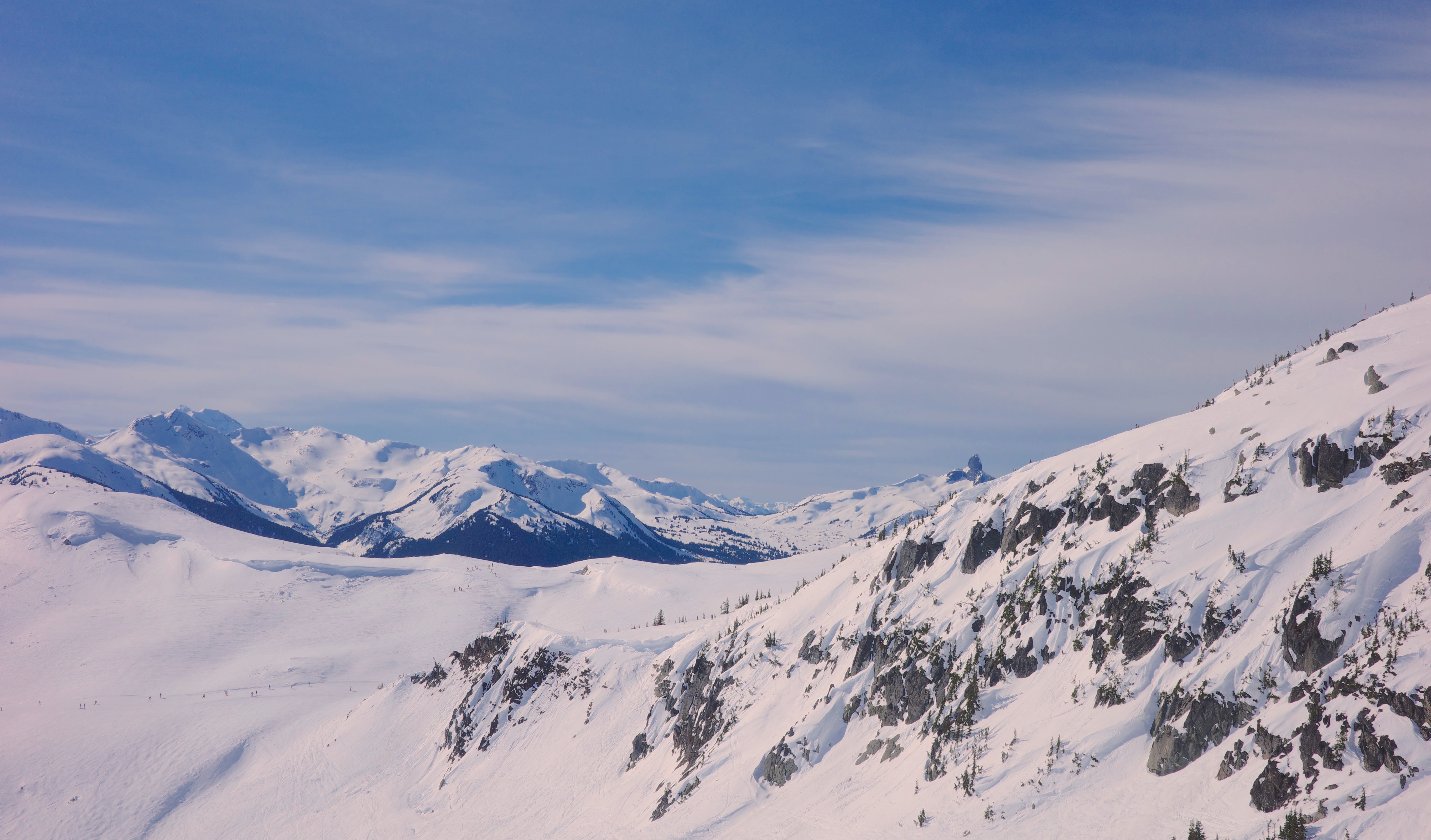 Snow-covered mountain peaks and rocky slopes beneath a blue sky